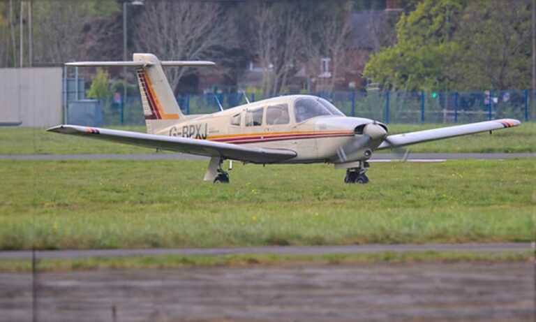 Small aircraft on grassy field, cloudy day
