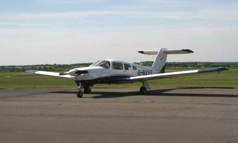 Small white plane on airstrip under clear skies
