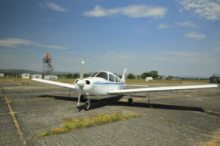 Small white airplane parked on sunny airstrip