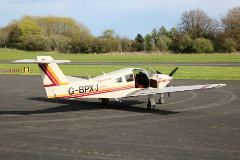 Small aircraft G-BPXL parked on runway in sunlight.