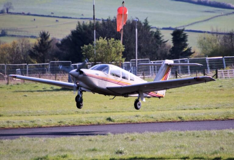 Small airplane landing on rural airstrip in daylight