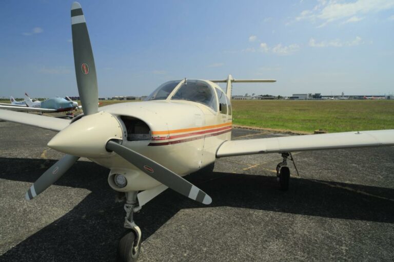 Small white airplane on tarmac under clear blue sky