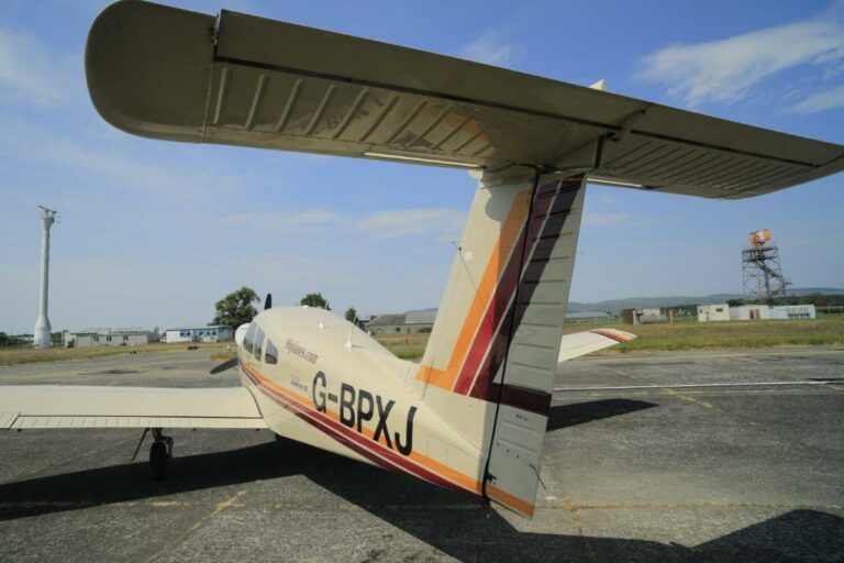 Small aeroplane G-BPXJ parked on runway under clear sky
