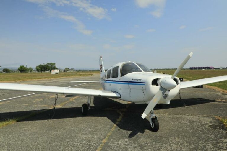 Small white airplane parked on sunny tarmac