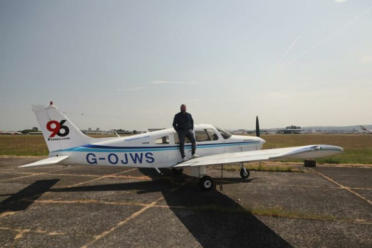 Man standing on small airplane wing at airstrip