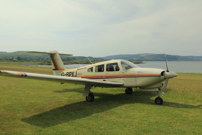 Small aircraft parked on grass overlooking a scenic lake