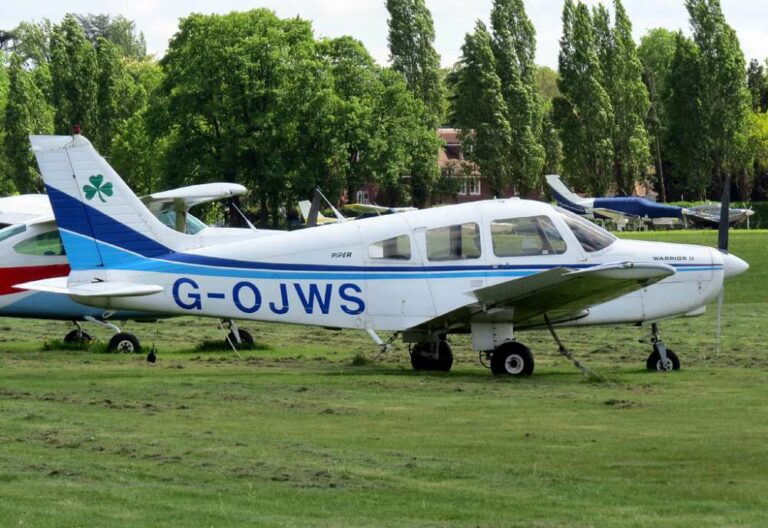 Small aircraft G-OJWS parked on grass airfield.