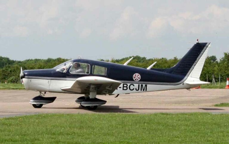 Small blue and white airplane parked on airstrip