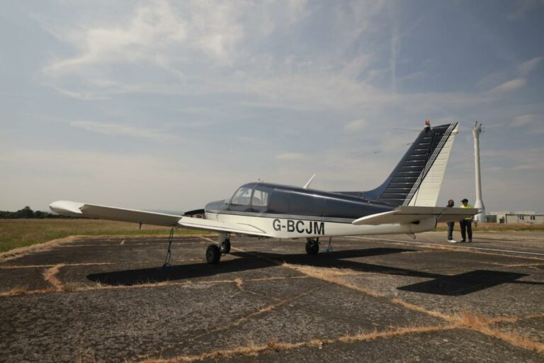 Piper airplane on runway with two people inspecting