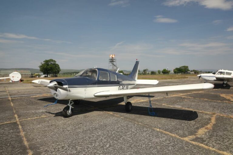 Small aircraft parked on sunny airfield