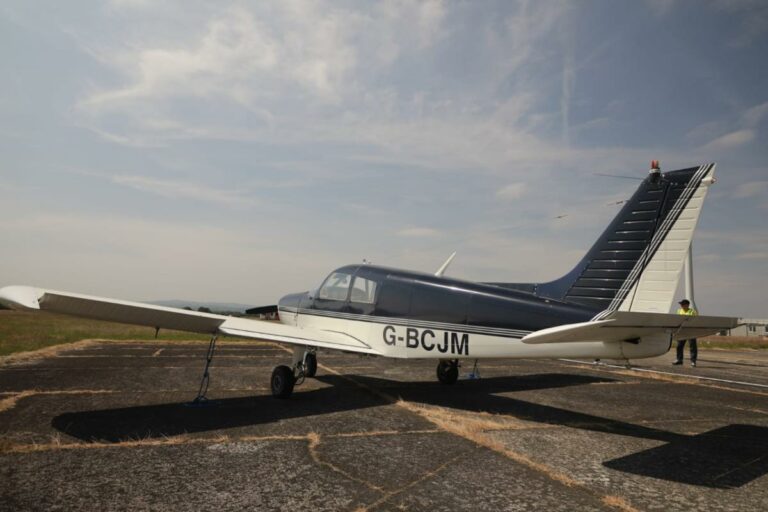 Single-engine aircraft parked on runway, clear sky.
