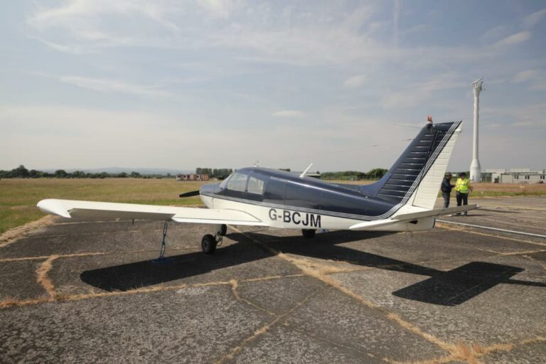 Small airplane on runway with two people nearby