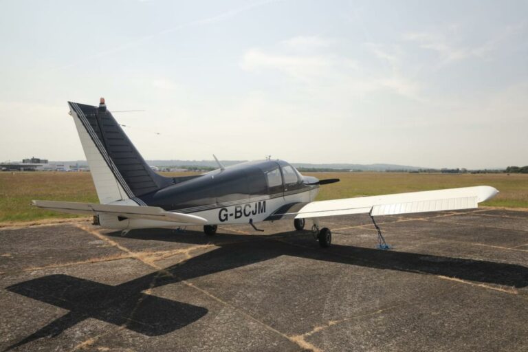 Small aircraft parked on sunny airstrip, registration G-BCJM