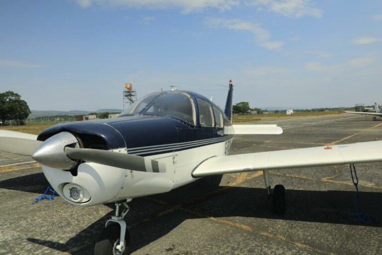 Small blue and white airplane parked on sunny runway