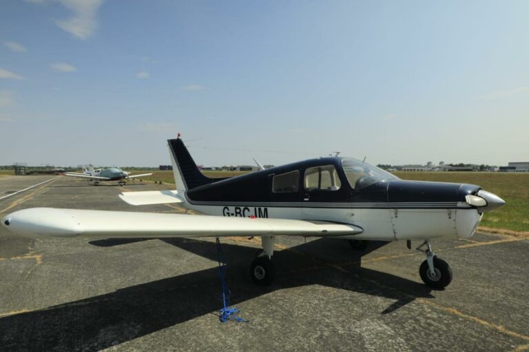 Small black and white airplane on sunny tarmac