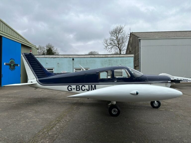 Small blue aircraft stationed at a hangar
