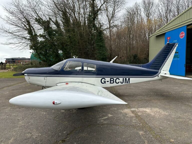 Blue and white airplane parked outside a hangar